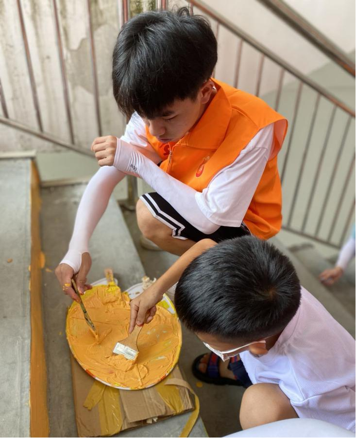 志愿服务团成员与小朋友一起进行阶梯绘画
